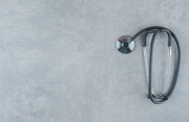 Black medical stethoscope on gray background